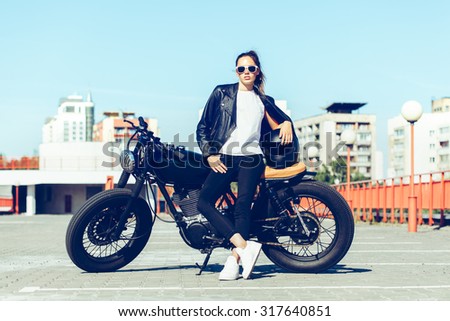 Biker sexy woman sitting on vintage custom motorcycle. Outdoor lifestyle toned portrait