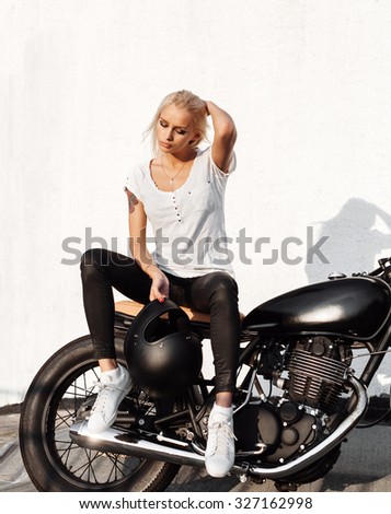 Portrait of female model Biker sitting on vintage custom motorcycle. Outdoor lifestyle portrait