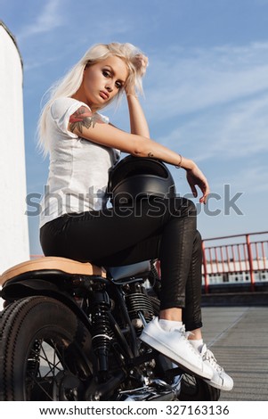 Portrait of female model sitting on vintage custom motorcycle. Outdoor lifestyle