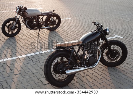 Two vintage custom motorcycles in the parking lot during sunset