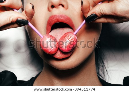 Woman licking two tasty lollipops. Close up against white background, not isolated