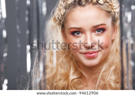 Beautiful blonde looks at the camera through the curtains of silver