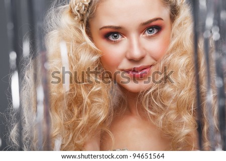 Beautiful blonde looking at the camera through the curtains of silver