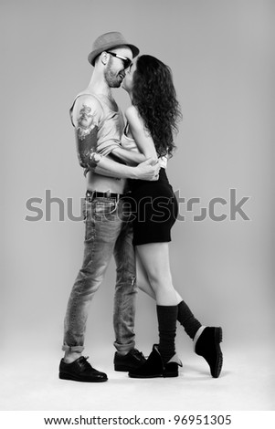 The portrait of a sexy girl and a hot man standing face to face  with his arm round her waist pulling her closer