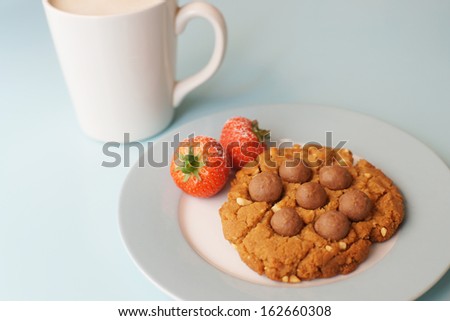 A cup of coffee and biscuits with chocolate and strawberry