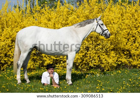Portrait of a nice white horse and young man on spring background