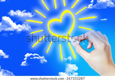 Hand painting a heart shape sun on sky suggesting hope
