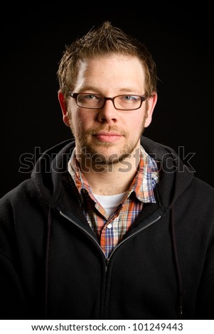 Young Man - This is a portrait of a young man with a beard and glasses with a small smirk on his face looking at the camera. Shot on a black background.