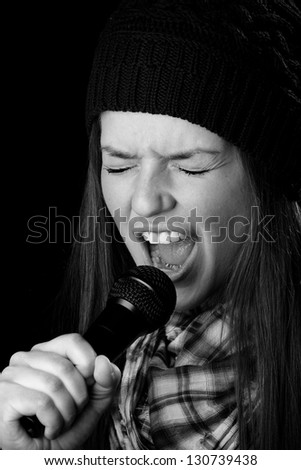 Singing - This is a black and white photo of a cute young adult singing into a microphone. Shot on a black background.