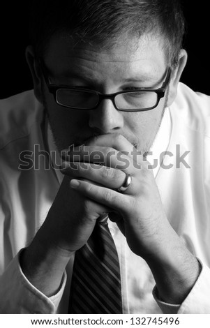 Divorce - This is a high contrast black and white image of a man praying after he has gotten some bad news. Shot on a black background.
