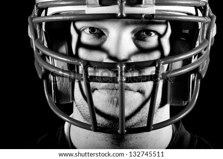 Football Player - This is a high contrast, black and white image of a young adult wearing a football helmet with an intense look on his face.
