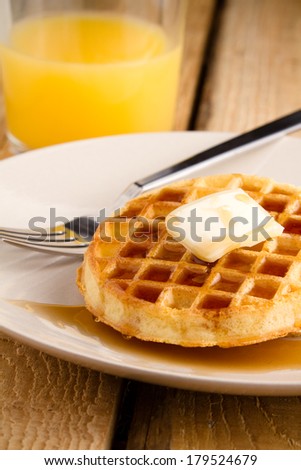 Waffles - This s a photo of a couple waffles soaked in syrup. Shot on a wooden table with a shallow depth of field.