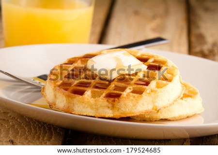 Waffles - This s a photo of a couple waffles soaked in syrup. Shot on a wooden table with a shallow depth of field.