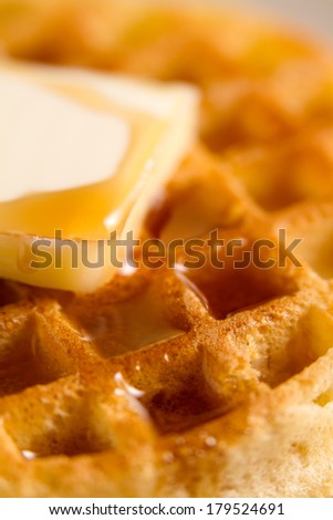 Waffle - This is a shot of a waffle with a slice of butter sitting on a plate getting covered with syrup. Shot with a shallow depth of field.