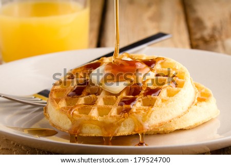 Waffles - This s a photo of a couple waffles being soaked in syrup. Shot on a wooden table with a shallow depth of field.