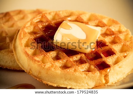 Waffles - This is a shot of a couple waffles with a slice of butter sitting on a plate getting covered with syrup. Shot with a shallow depth of field in a warm retro color tone.