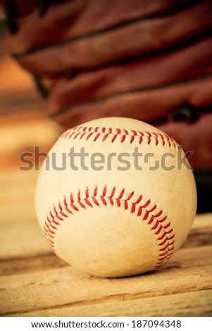Baseball - This is a shot of an old worn baseball sitting in front of an old glove. Shot with a shallow depth of field in a warm retro color tone.