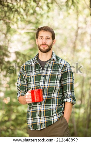 Young Man Drinking Coffee - This is a shot of a young man enjoying a hot cup of coffee outside on a camping trip.