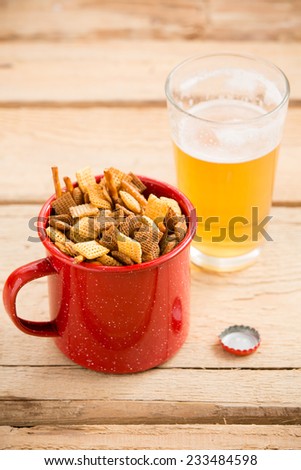 Party Food Mix and Beer - This is a shot of a mug full of a holiday party mix and a glass of beer shot on a wooden table. Shot with a shallow depth of field.