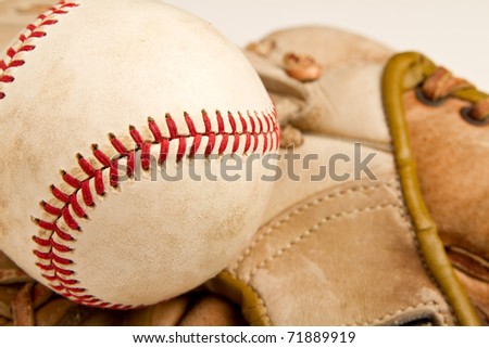 This is a close up shot of an old baseball with an old baseball glove in the background. Shot with a shallow depth of field.