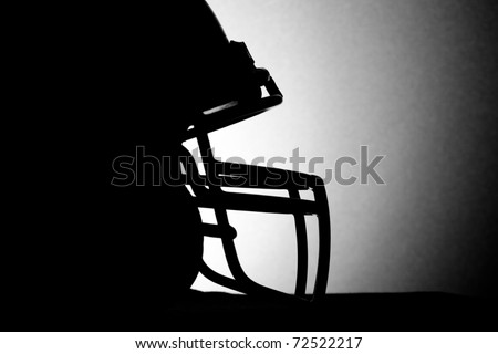 This is a black and white silhouette shot of a football helmet.