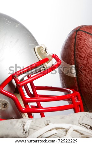 This is a shot of an old scratched up football helmet with a football leaning against it.