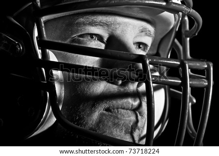 This is a high contrast, black and white image of a young man with an intense look on his face wearing a football helmet. Processed to enhance skin texture.
