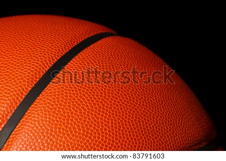 This is a close up shot of a leather basketball. Light falls off towards the back of the ball. Shot on a black background.