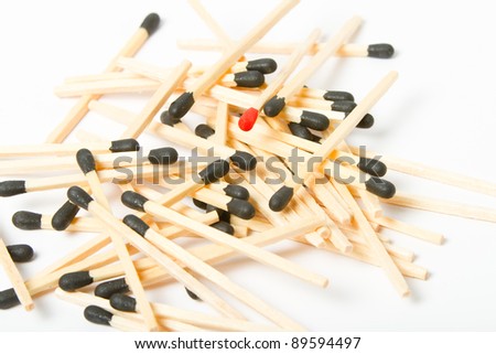 This is a pile of wooden matches on a white background with one red match in the middle. Shot with a shallow depth of field. (Focus On The Red Match)