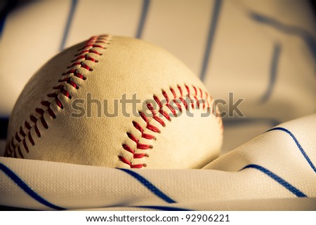 Baseball - This is a shot of an old baseball sitting on a wrinkled baseball jersey. Shot with a warm retro color tone with a shallow depth of field and vignetting.