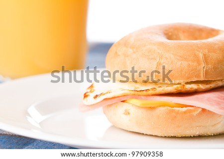 Egg Sandwich / This is a photo of a delicious egg ham and cheese sandwich on a toasted bagel with a glass of juice in the background.