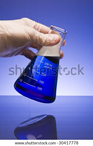 Gloved hand holding a beaker filled with blue bubbling liquid against a blue gradient background.