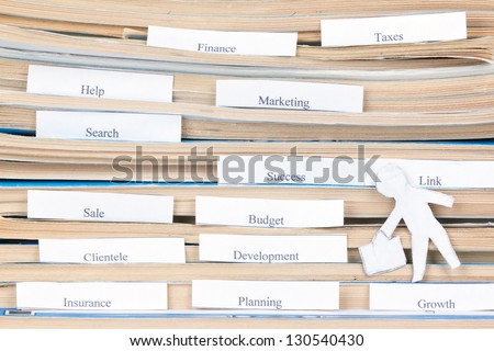 concept of modern business. Businessman figurine carved out of the paper is on the stack of documents.