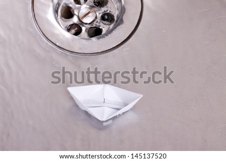 Toy paper boat sinks in the sink