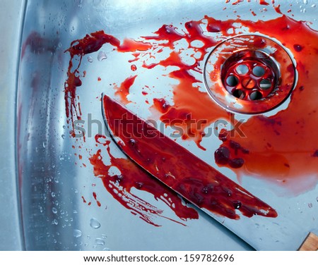 bloody kitchen knife rests in a steel shell. halloween or crime scene.