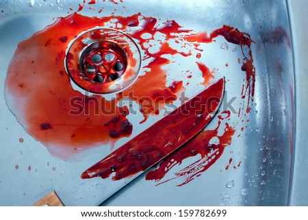 bloody kitchen knife rests in a steel shell. halloween or crime scene.
