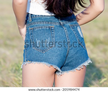 beautiful buttocks of a young girl dressed in a short denim shorts.  closeup  girl stand in field