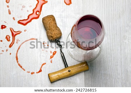 glass of wine and a corkscrew with cork from wine stains on the table