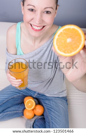 Woman drinking orange juice smiling showing oranges. Young beautiful Caucasian model.