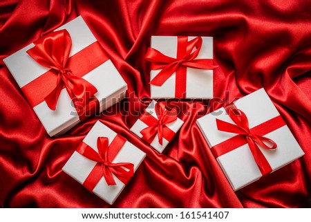 White gift box with red ribbon on red silk color background