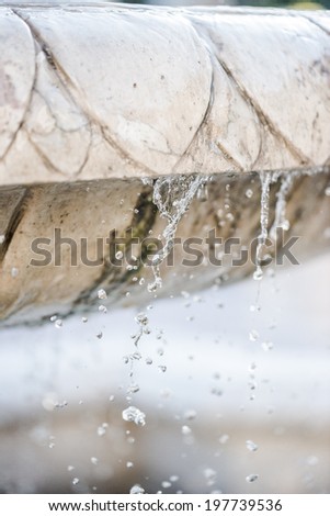 Close-up of an old stone fountain with dripping water and blurred background