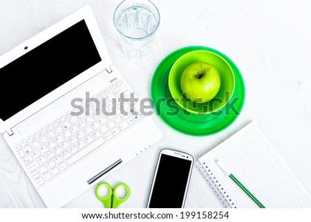 Office supplies, devices, coffee cup and apple on wooden table