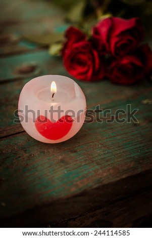 Beautiful romantic red candles with red rose on rustic wooden background