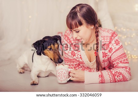 Smiling girl  and happy dog, having christmas snacks in christmas decorated living room