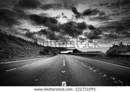 A road winds off into the distance, black and white