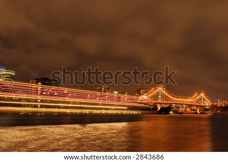 Long exposure of river with bridge in background and moving boat