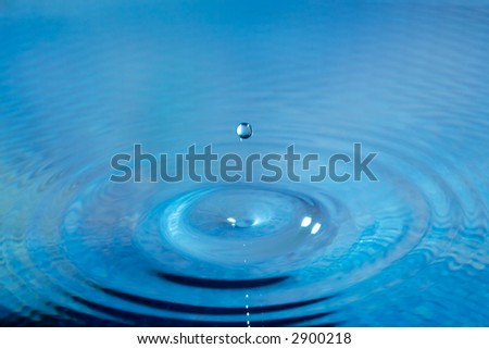 Water drop falling into a fresh blue body of water