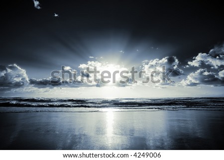 Morning sun bursts through clouds on a beach