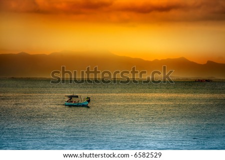 Golden Asian sunset over ocean with boat