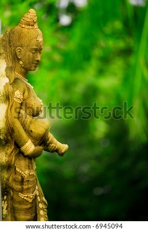 Statue of Asian woman against green foliage background